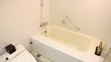 A bathroom with a bathtub, toilet, and a handrail.