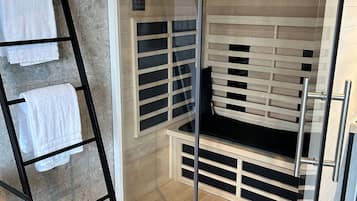 Une salle de bain moderne avec une douche à parois de verre, des étagères en bois et un escabeau en métal noir.