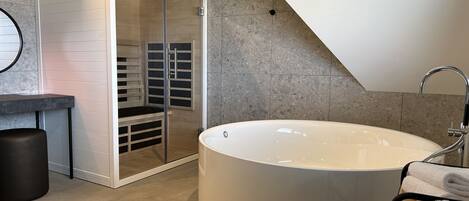 Un baño moderno con una bañera independiente, cabina de ducha con paredes de cristal y un diseño minimalista.