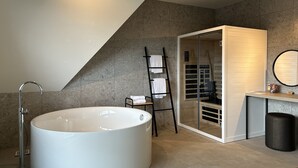 Un baño moderno con una bañera independiente, un perchero para toallas, un tocador con espejo y un box de ducha de vidrio.