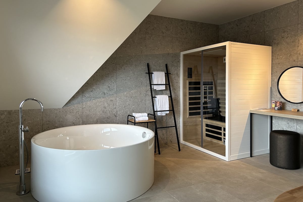 A modern bathroom with a freestanding bathtub, a towel rack, a vanity with a mirror, and a glass shower enclosure.