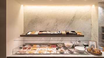 Un buffet de petit-déjeuner proposant une variété d’aliments et agrémenté d’un revêtement mural en marbre.