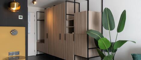 A modern room with a wooden wardrobe, a potted plant, and a teal chair.