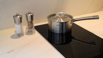 A kitchen with a black induction cooktop, a stainless steel pot, and two salt and pepper shakers.