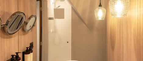 A modern bathroom with a round sink, wooden walls, and pendant lighting.