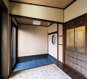 A traditional Japanese room with tatami flooring, a shoji screen door, and a small tatami mat entrance.
