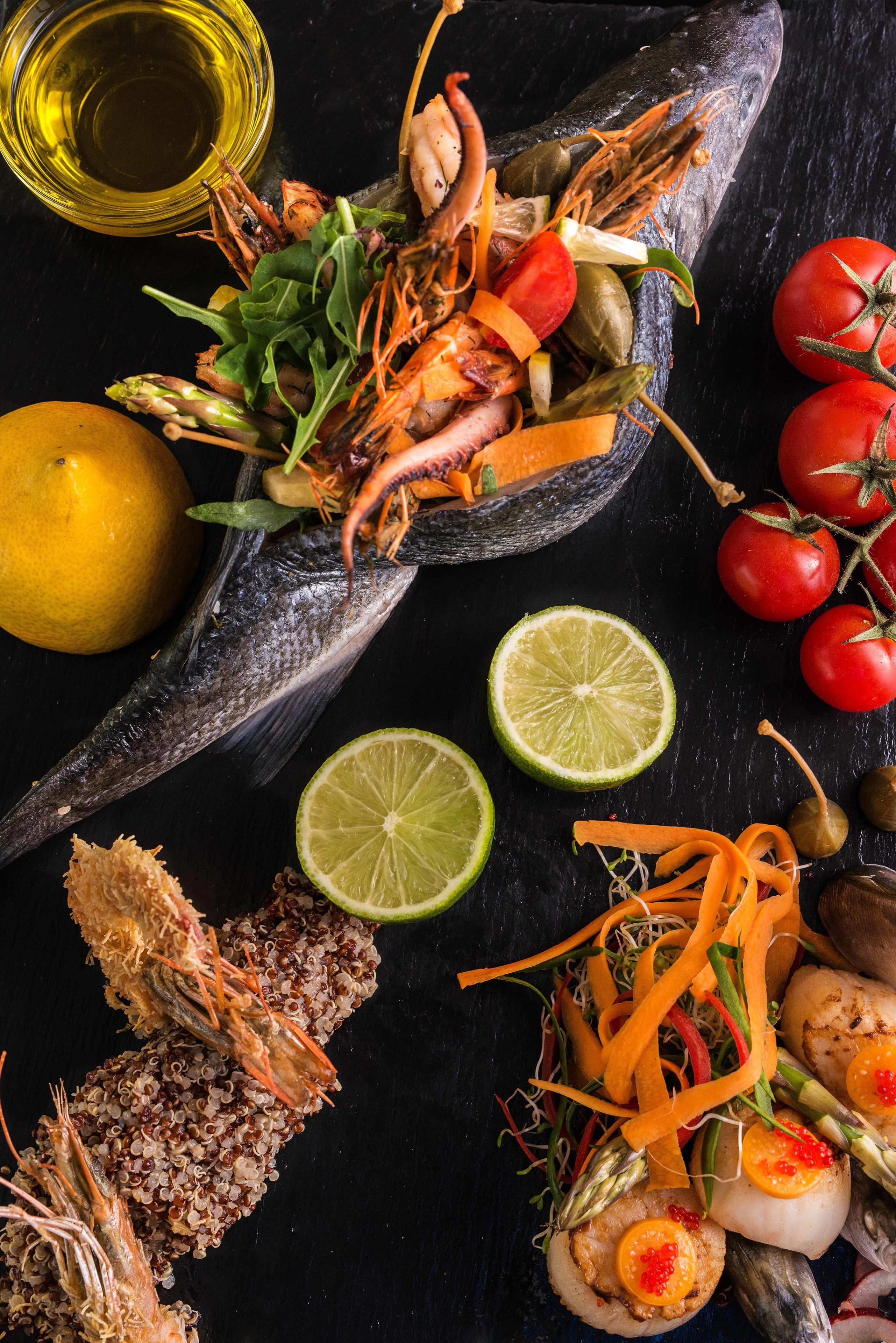 A seafood dish with shrimp, scallops, and vegetables on a dark surface.