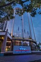 Exterior del Hotel Dimyat Vara con fachada de vidrio moderna y un letrero llamativo.
