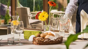Une table dressée avec de beaux verres, un panier de pain et deux fleurs.