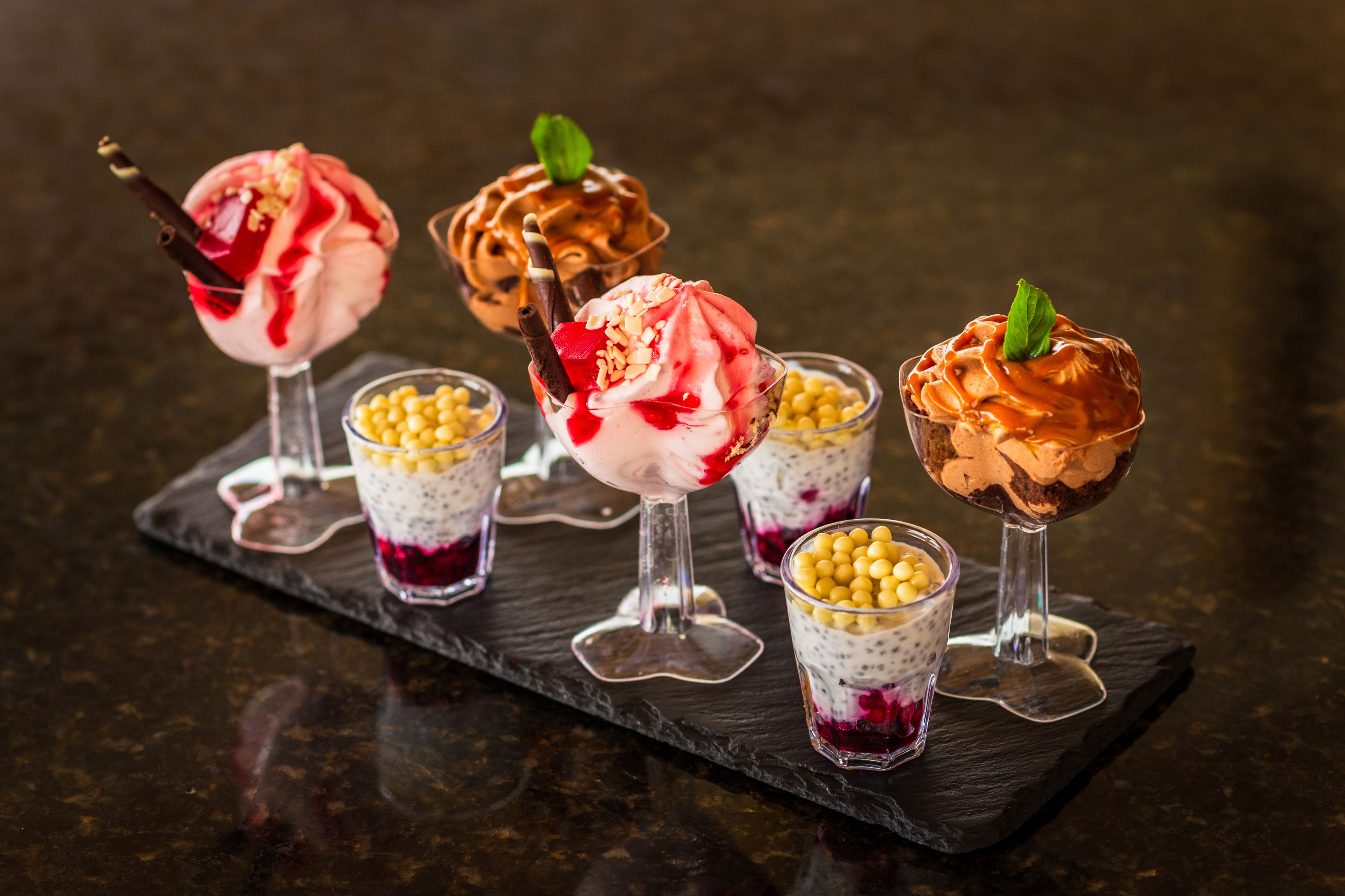 Four dessert cups on a slate serving board.