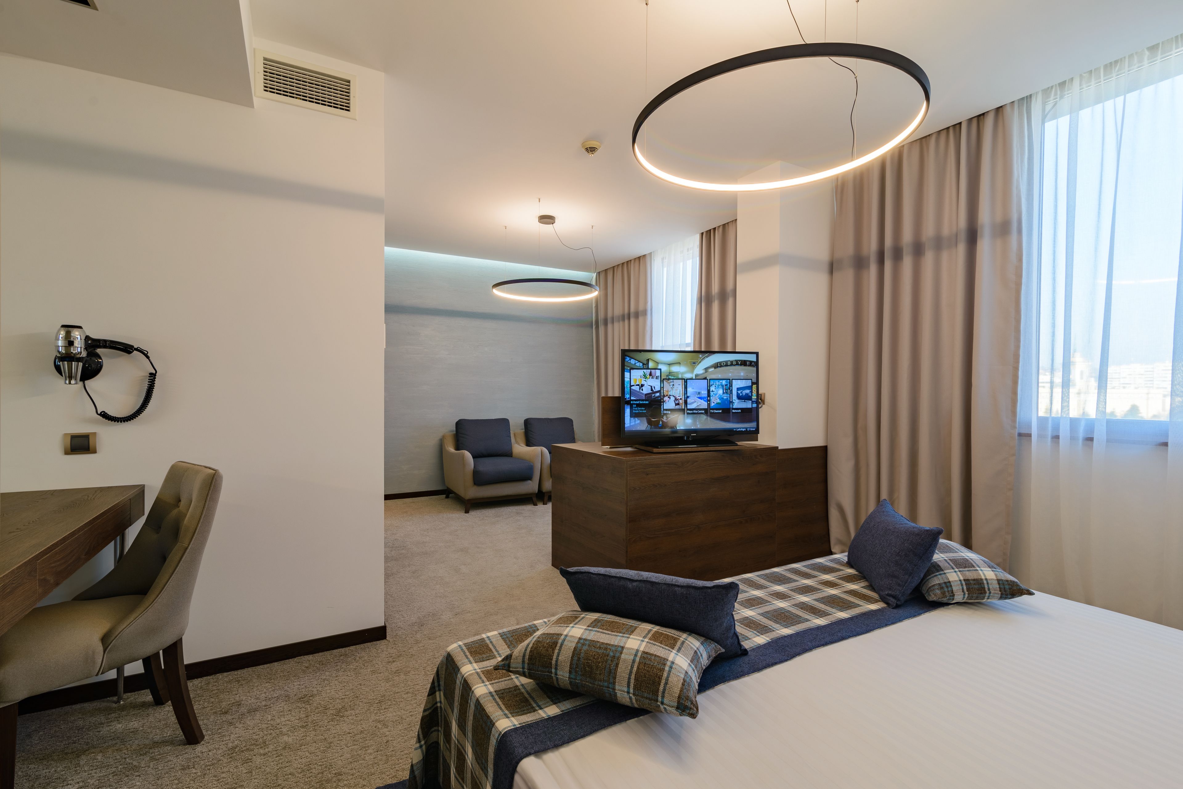 Una habitación de hotel con una cama, un escritorio, un televisor y una silla.