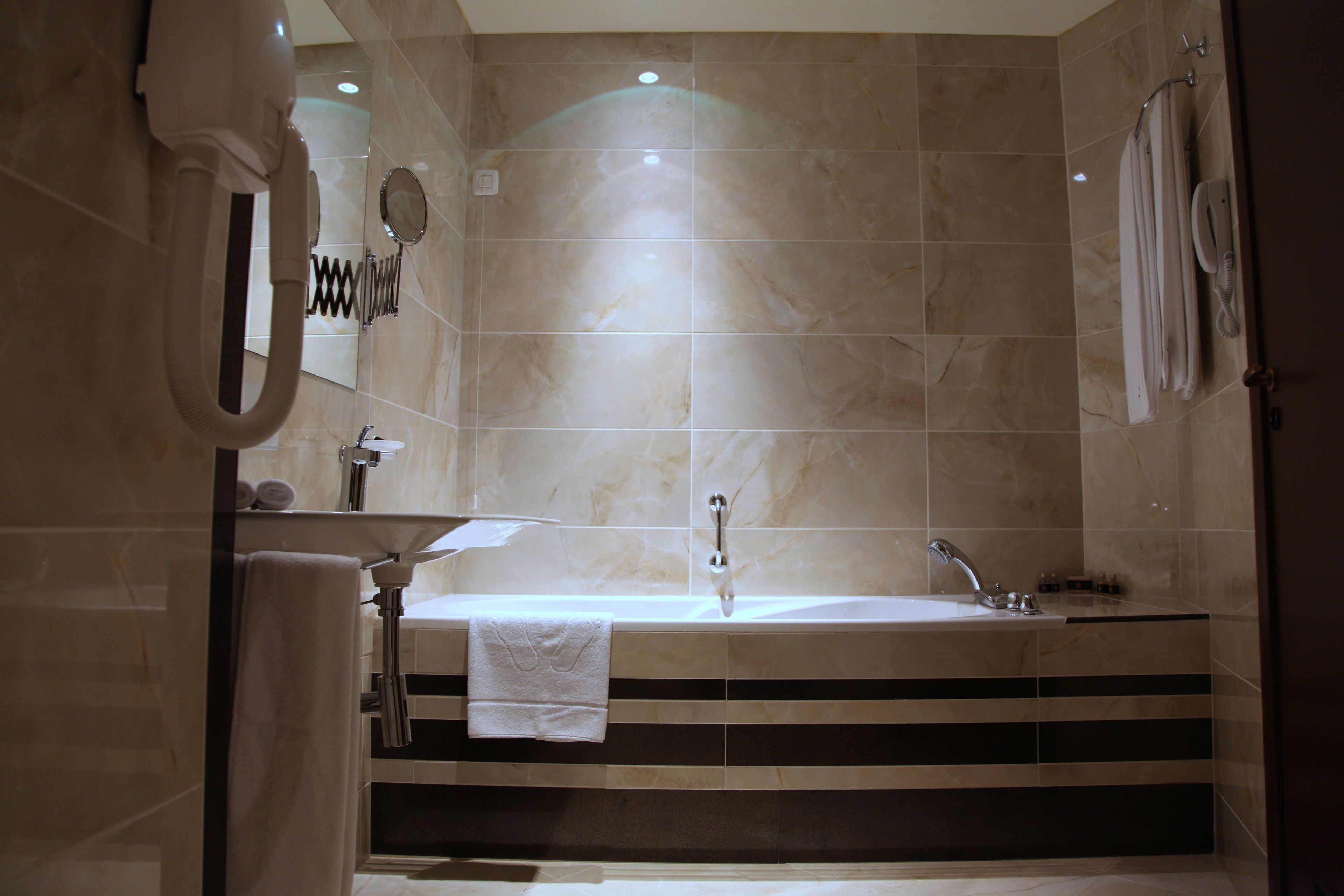 A modern bathroom with a large sink, a mirror, and a towel rack.