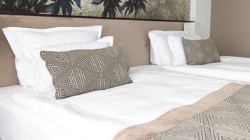 A hotel room with two beds, each with white bedding and patterned pillows.