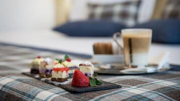 A dining table with a plaid tablecloth, a cup of coffee, and a plate of desserts.