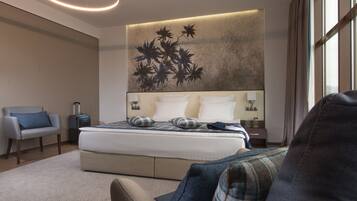 Una habitación de hotel moderna con una cama grande, un sofá, una silla y una obra de arte en la pared.