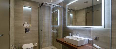 Un baño moderno con ducha de vidrio, un espejo grande y un mueble de tocador de madera.