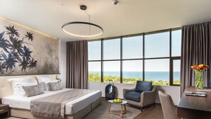 Une chambre d’hôtel moderne avec un grand lit, un bureau, une chaise et une vue sur l’océan.