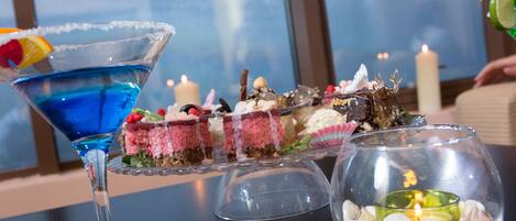 Una mesa de postres con un cóctel azul, varios pasteles y una vela.