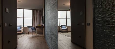 A modern hotel corridor with wooden flooring, large windows, and contemporary furniture.