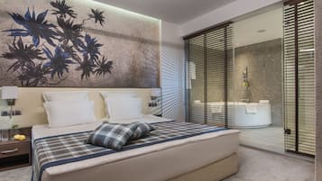 Un dormitorio moderno con una cama grande, una obra de arte en la pared y un cerramiento de vidrio corredero que da al baño.