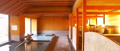 A traditional Japanese onsen with wooden interiors and multiple hot spring baths.