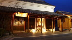 A traditional Japanese building with a tiled roof and wooden structure, illuminated by warm lighting. - Juhachiro (Gifu)