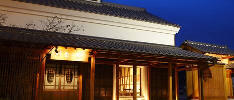 Un edificio japonés tradicional con techo de tejas y estructura de madera, iluminado por una cálida luz.