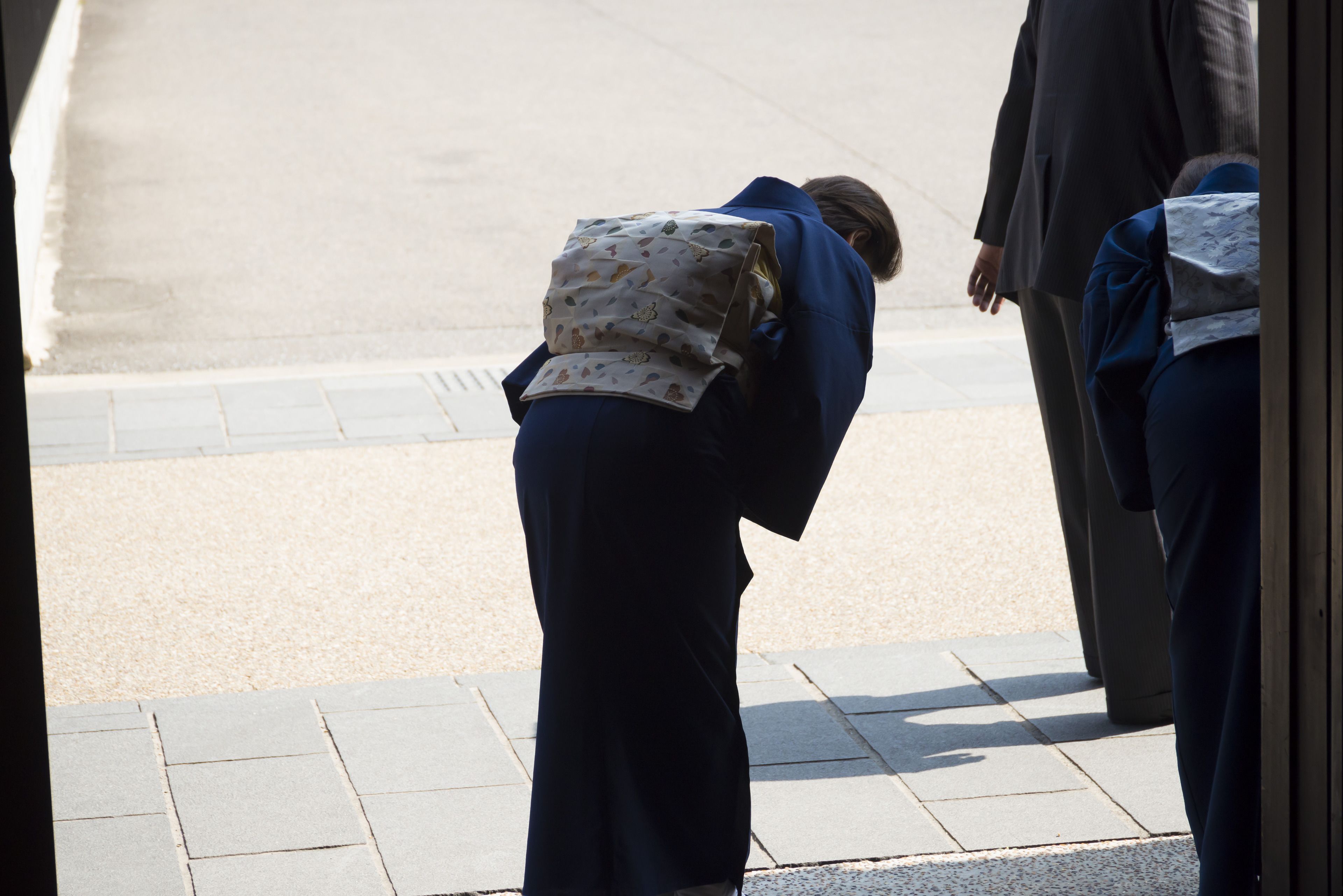 A person bending over, possibly in a restroom, with a patterned bag.
