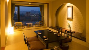 A modern hotel room with a dining area, large windows, and a view of the cityscape. - Juhachiro (Gifu)
