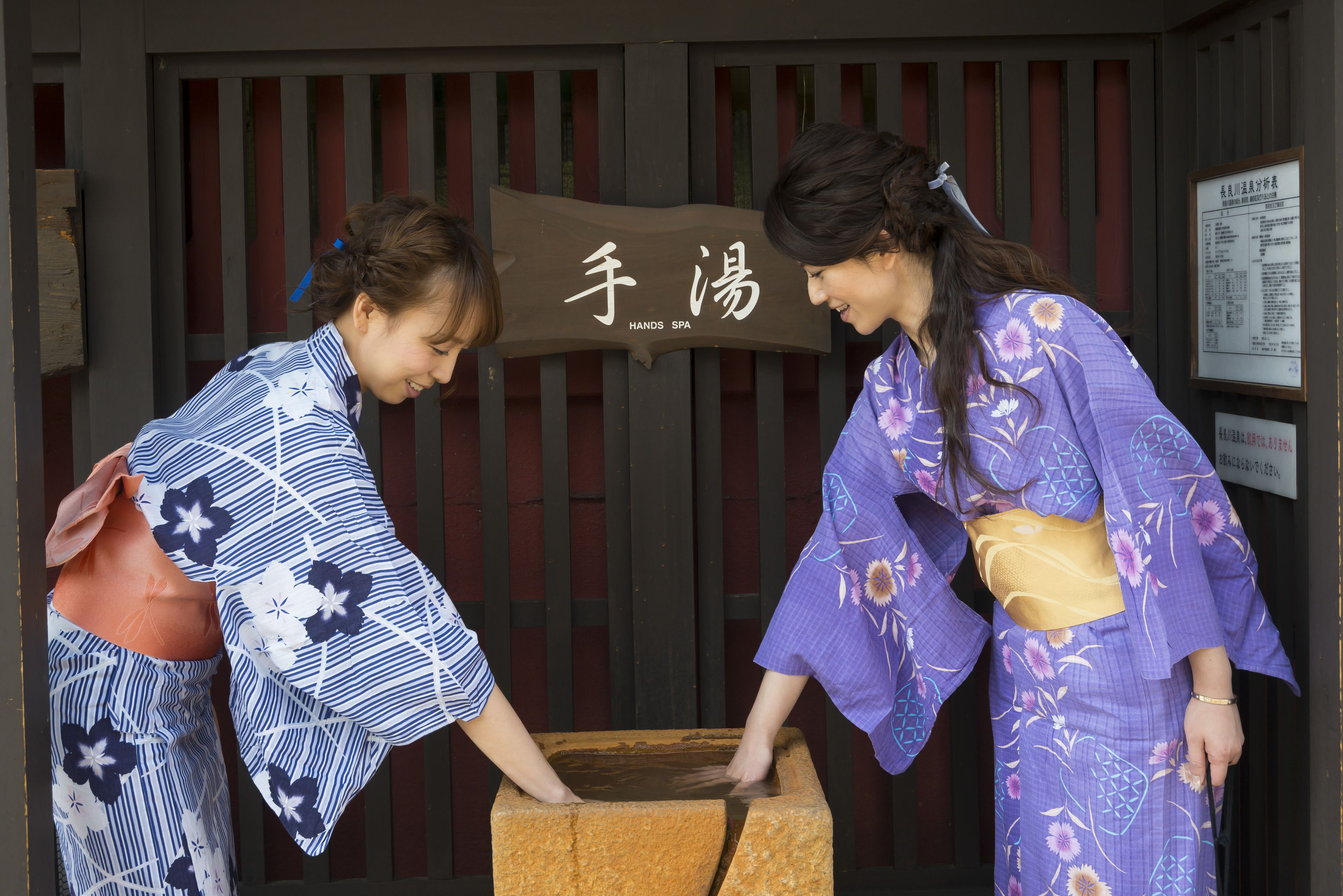 Two individuals in traditional Japanese attire standing in front of a sign that reads "HAND SPA".