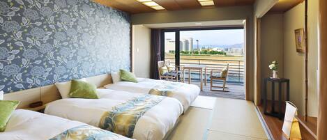 Habitación de hotel con tres camas, balcón y vistas a la ciudad.