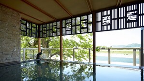 A serene indoor pool area with a clear view of a lake and mountains. - Juhachiro (Gifu)