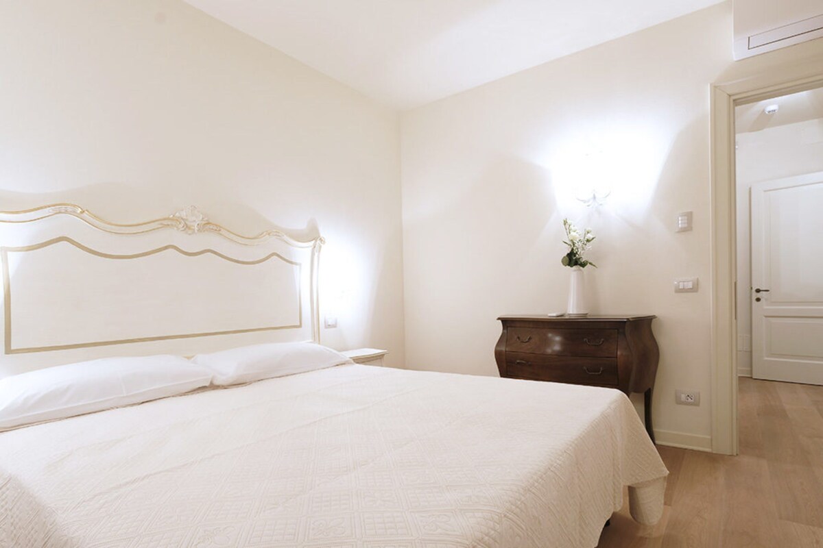 A bedroom with a bed, a nightstand, a dresser, and a door.