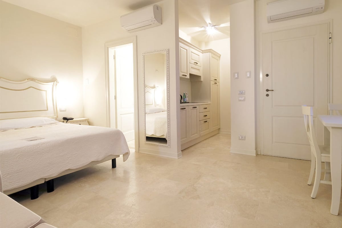 A bedroom with a bed, a desk, and a wardrobe.