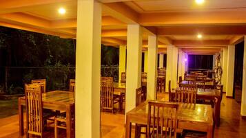A restaurant with wooden tables and chairs, a tiled floor, and a view of the outdoors.