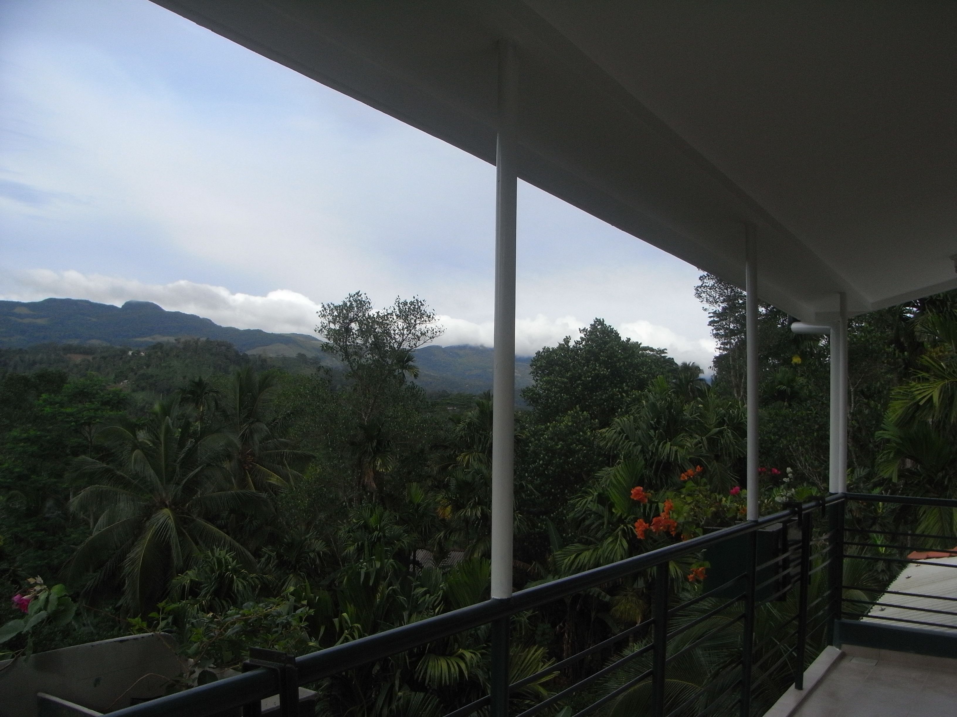A balcony with a view of a lush landscape and distant mountains.