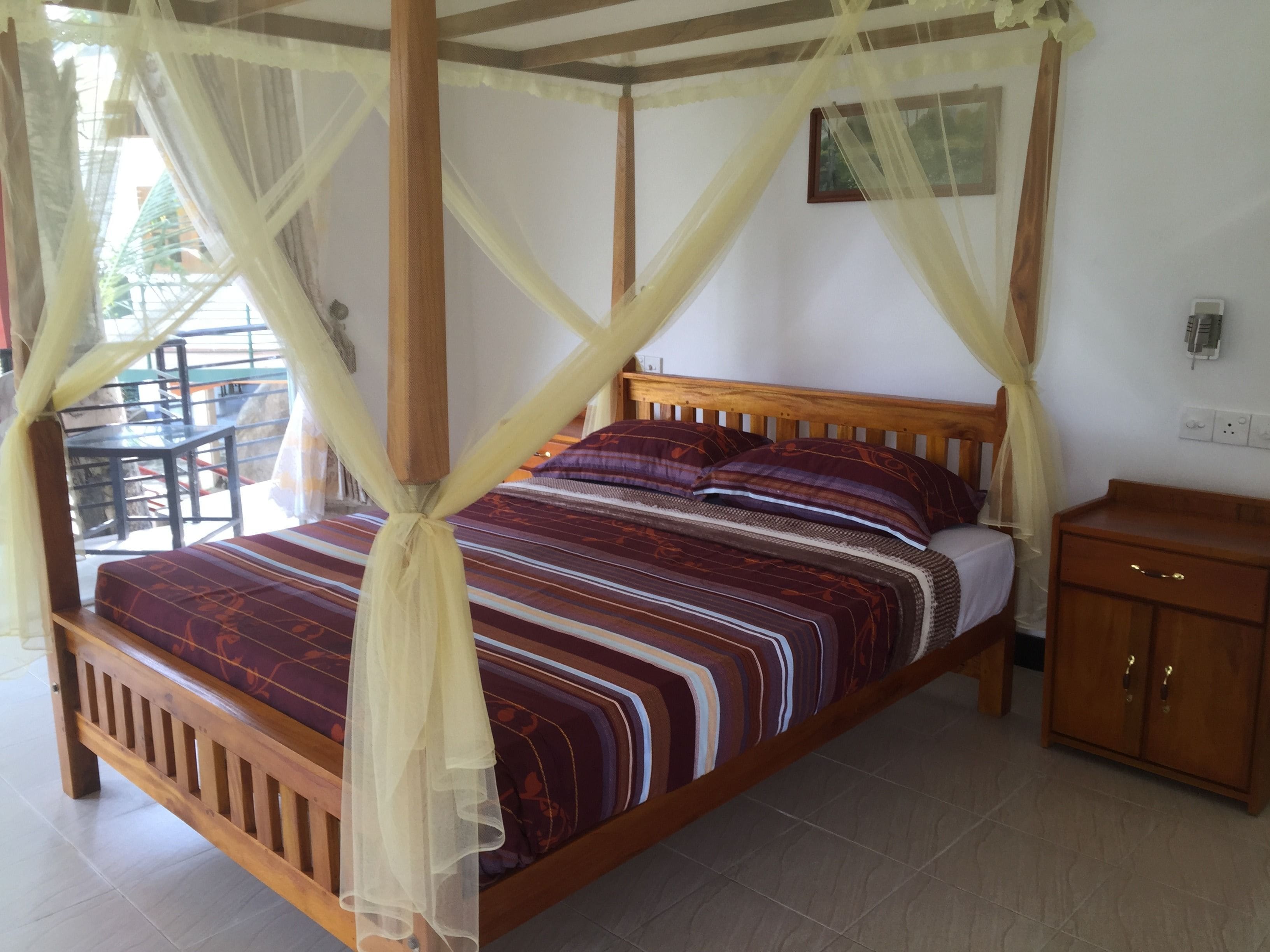 Un letto con baldacchino, una testata in legno e una coperta a motivi.