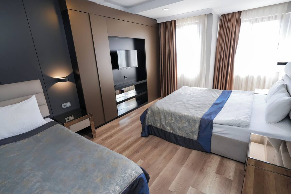 A hotel room with two beds, a TV, and a minibar.