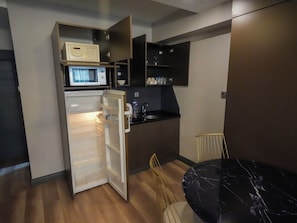 Eine kompakte Küche mit Mikrowelle, Kühlschrank und einem Essbereich mit einem Marmortisch.