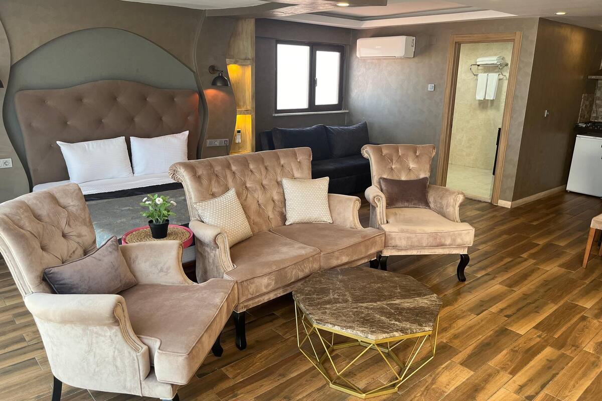 A modern living room with a sectional sofa, armchairs, a coffee table, and a large headboard.