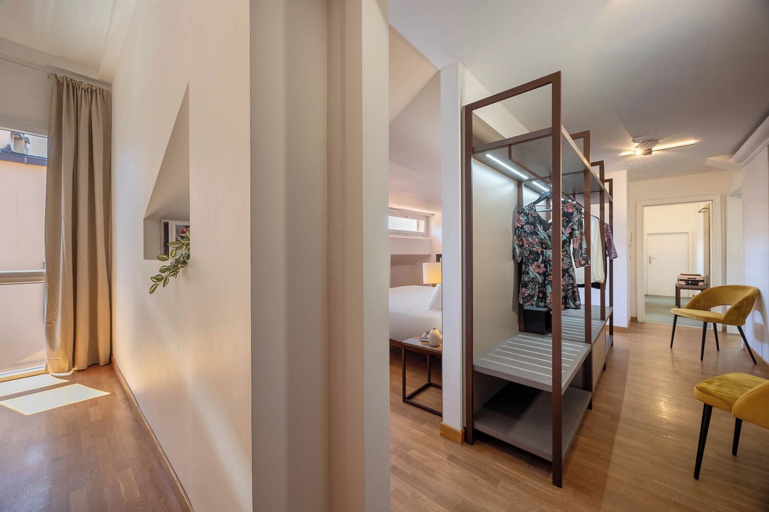 A hotel room with a bed, a desk, a chair, and a wardrobe.