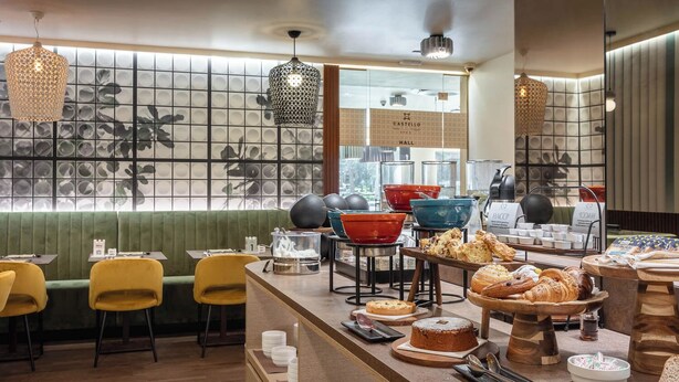 A breakfast buffet with various food items and a seating area with chairs and tables. - Hotel Castello (L'Aquila)