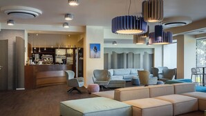 A modern living room with a bar area, sectional sofas, and pendant lighting. - Hotel Castello (L'Aquila)