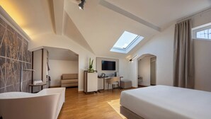 A modern hotel room with a skylight, a desk, a sofa, and a large bed. - Hotel Castello (L'Aquila)