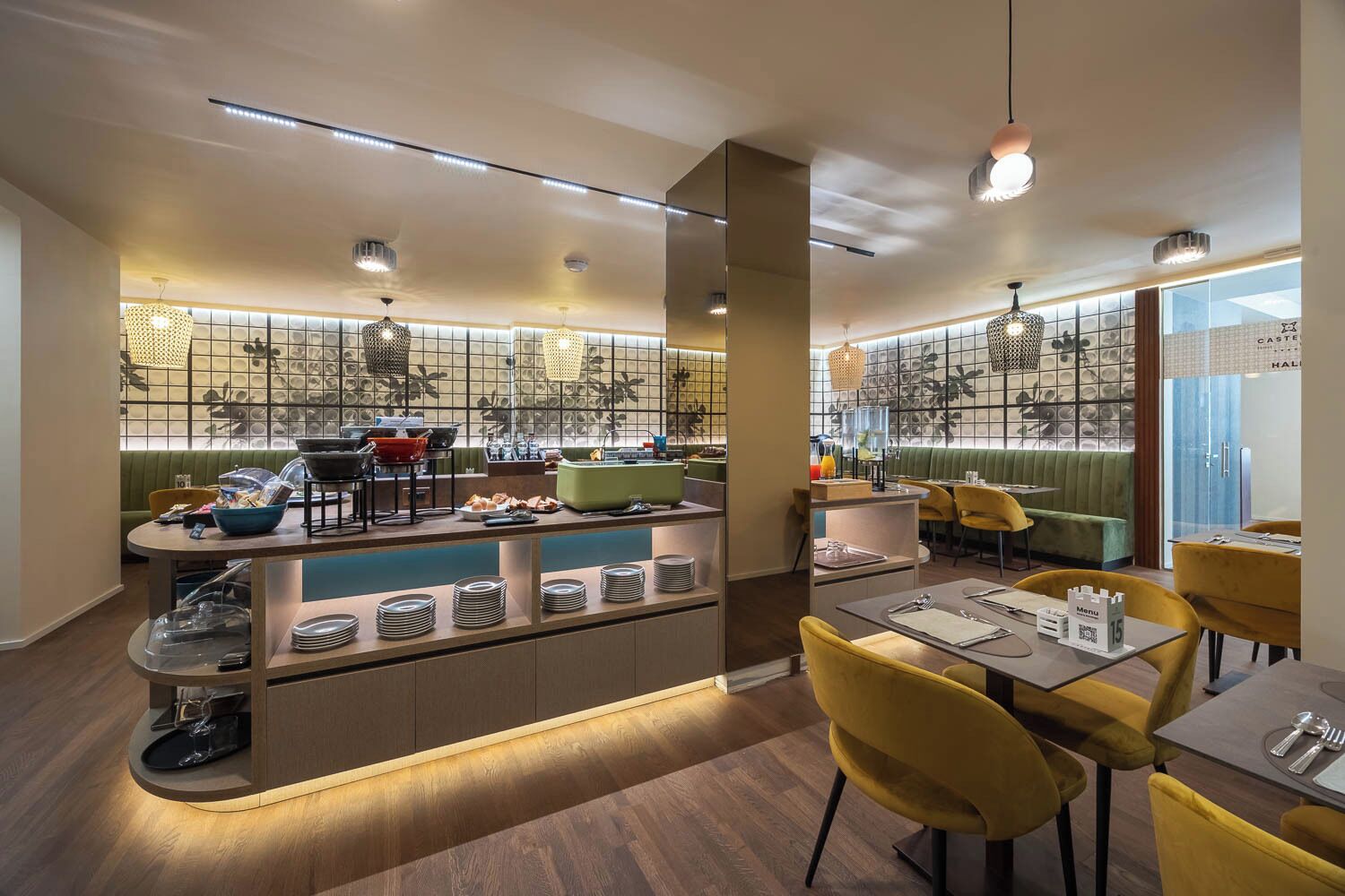 A modern restaurant with a central bar area, seating arrangements, and a patterned wall design.