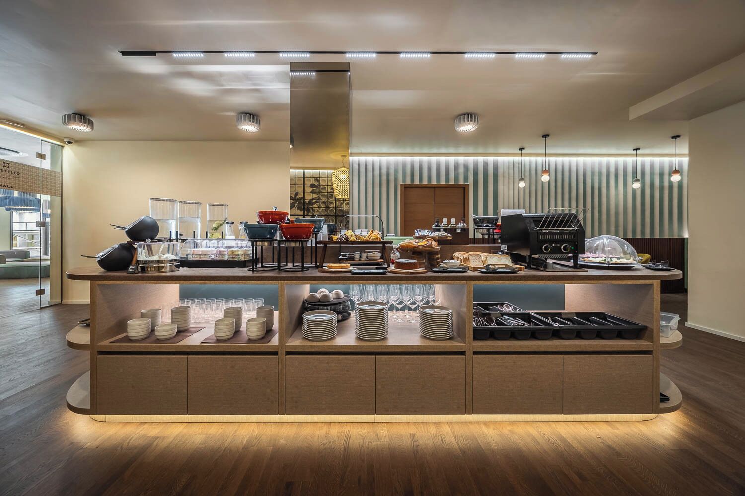 A modern breakfast bar with a variety of food items and beverages, a coffee machine, and neatly arranged tableware.