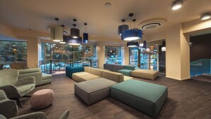 A modern lounge area with seating, large windows, and pendant lighting. - Hotel Castello (L'Aquila)