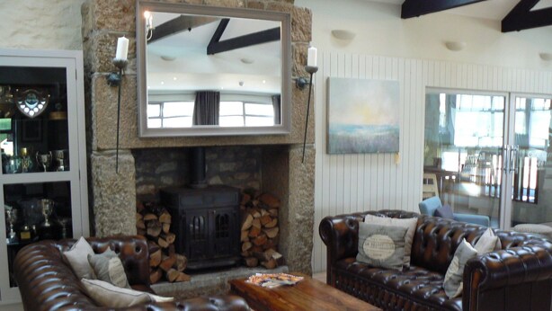 A cozy living room with a stone fireplace, leather sofas, and a wooden coffee table. - Cape Cornwall golf & Leisure (Cornwall)