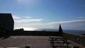 An outdoor seating area with stone walls, a picnic table, and a view of the sea. - Cape Cornwall golf & Leisure (Cornwall)