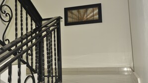 A staircase with black metal railings and a framed picture on the wall. - Le Suites Serviced Apartments (Accra)